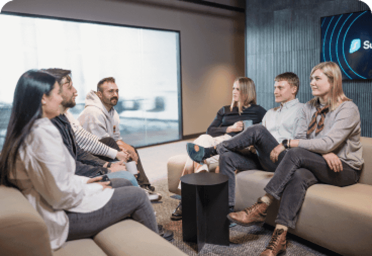 Six people sitting on two white couches facing one another.