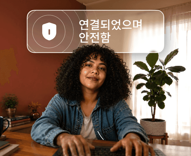 곱슬머리의 한 사람이 책상에서 노트북에 타이핑하고 있으며 그 위에는 '연결되었으며 안전합니다'라는 말풍선이 있는 모습.