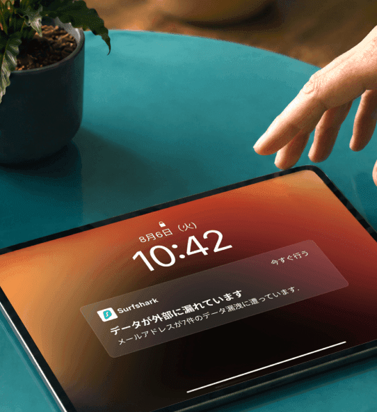 「データが漏洩しています」という通知が表示されたタブレットに手を伸ばしている様子。