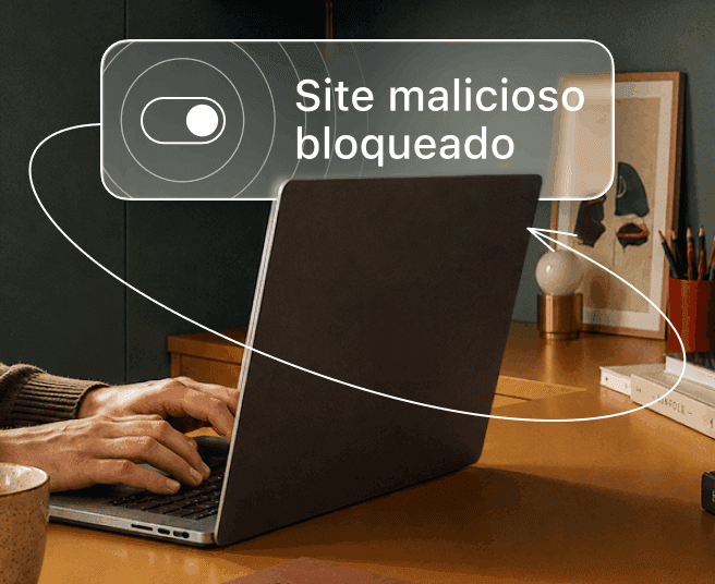 Uma pessoa digita em um notebook enquanto uma sobreposição digital exibe um botão de ativação e o texto Site malicioso bloqueado.