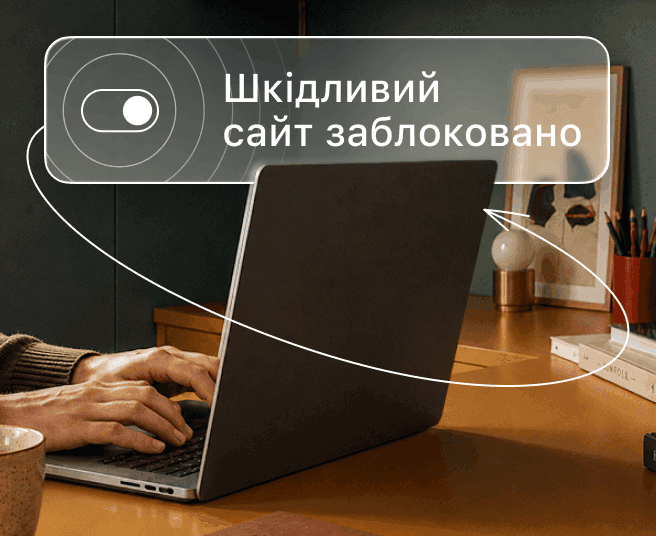 Людина друкує на ноутбуці, а на цифровому накладенні відображається перемикач і текст «Шкідливий сайт заблоковано».