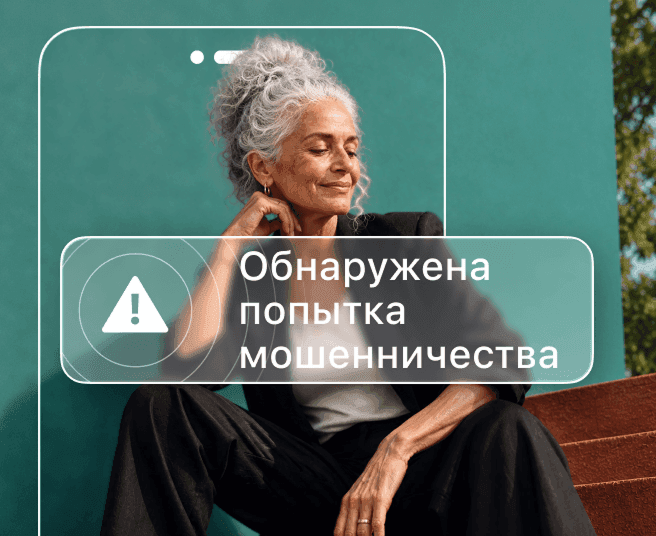 Женщина с седыми волосами сидит на фоне бирюзовой стены; ее частично скрывает контур телефонас оповещением «Обнаружено мошенничество».