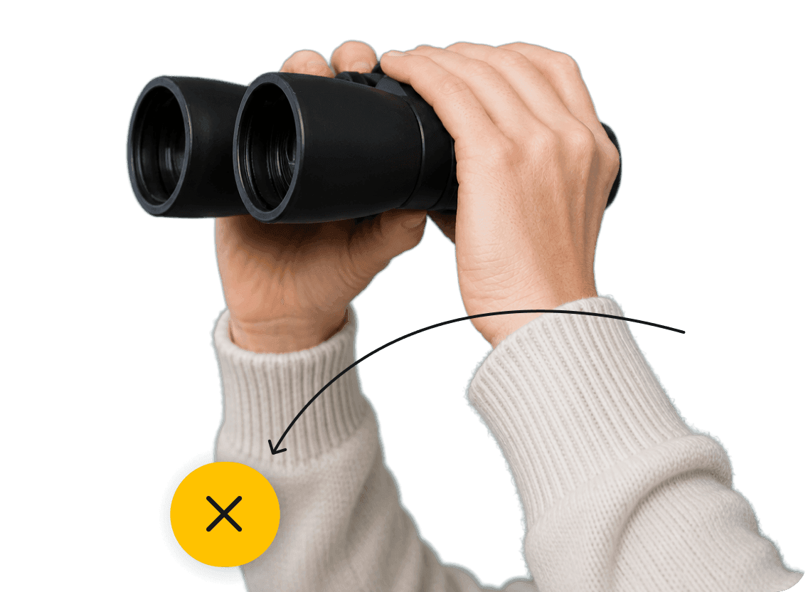 Hands holding binoculars with a curved arrow pointing down toward a yellow circle containing an X icon.