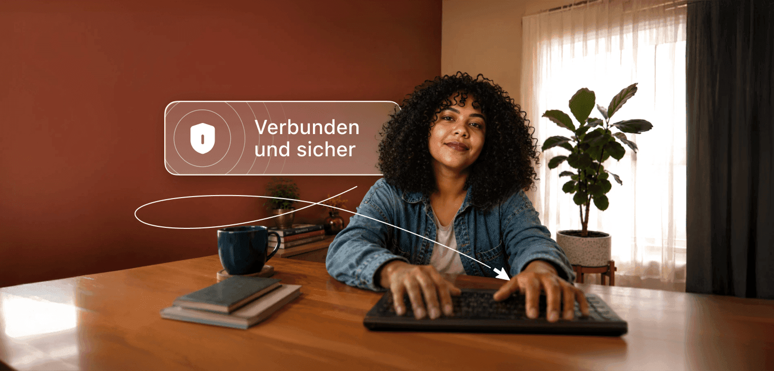 Eine Person mit lockigem Haar tippt an einem Schreibtisch auf einem Laptop, darüber eine Sprechblase mit der Aufschrift „Verbunden und sicher“.