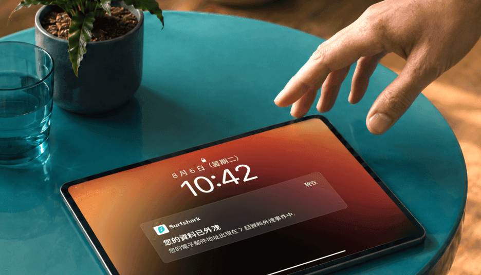 一隻手伸向平板電腦,螢幕顯示一條通知:「您的數據已外洩」。