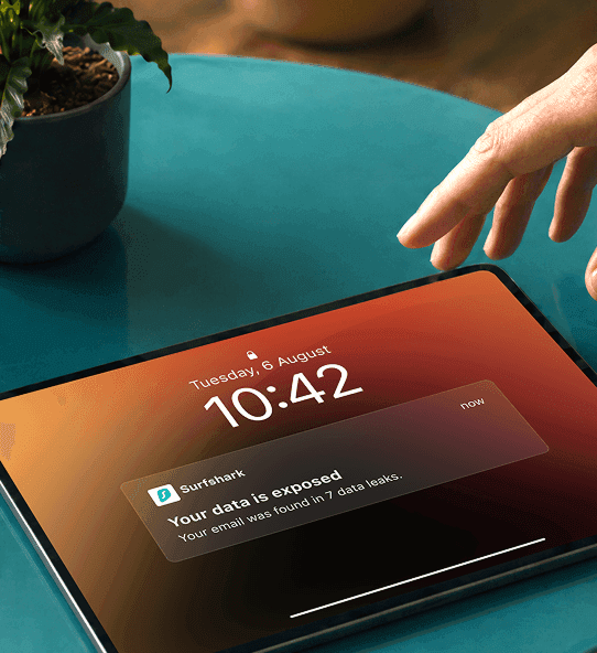 A hand reaching for a tablet displaying a notification that reads Your data is exposed.