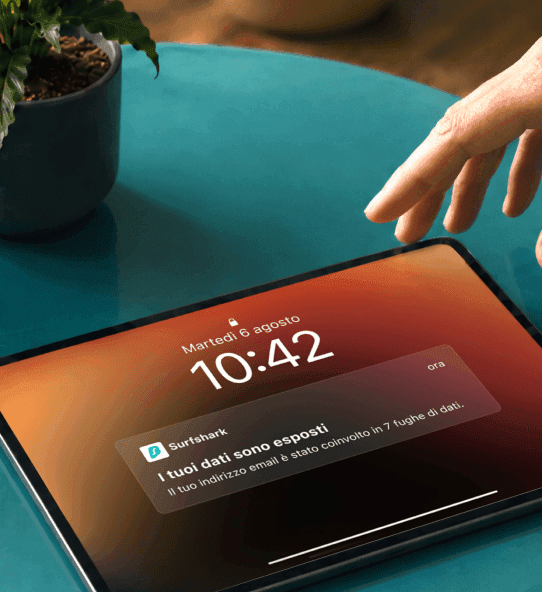 Una mano si avvicina a un tablet su cui viene visualizzata una notifica con il testo I tuoi dati sono esposti.