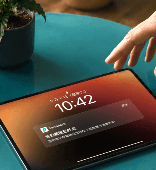 一只手伸向平板电脑,屏幕显示“您的数据已外泄”通知。