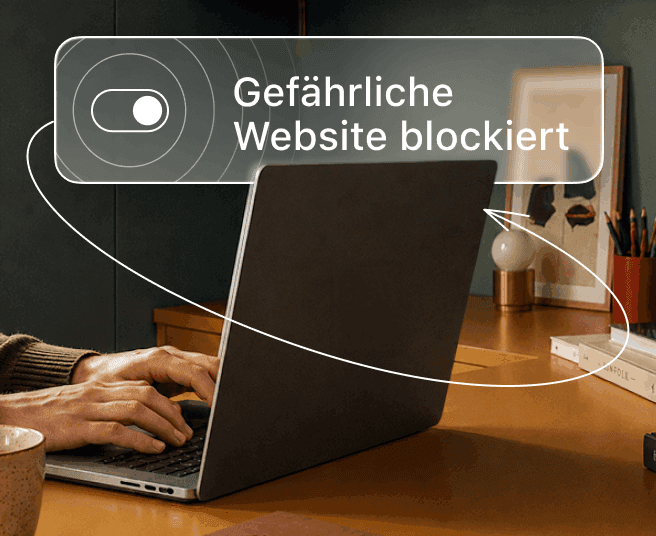 Eine Person tippt auf einem Laptop, während ein digitales Overlay einen Kippschalter und den Text „Bösartige Website blockiert“ anzeigt.