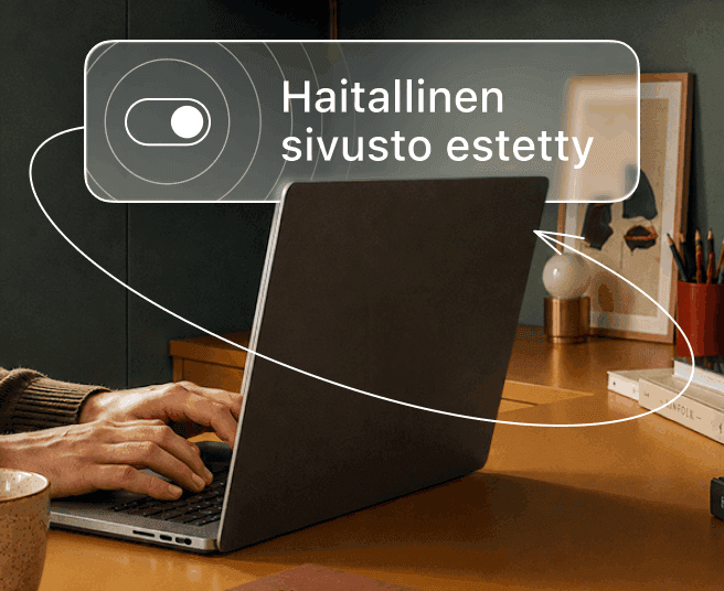 Henkilö kirjoittaa kannettavalla tietokoneella samalla, kun digitaalisessa peittokuvassa näkyy valintapainike ja teksti ”Haittasivusto estettiin”.