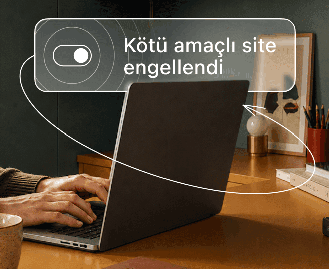 Bir kişi dizüstü bilgisayarda yazı yazarken dijital bir katmanda açma/kapatma anahtarı ve Kötü amaçlı site engellendi metni gösteriliyor.