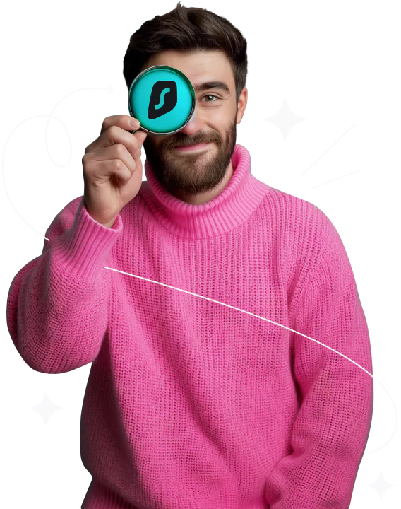 A man in a pink sweater holding a magnifying glass with the Surfshark logo on its lens.