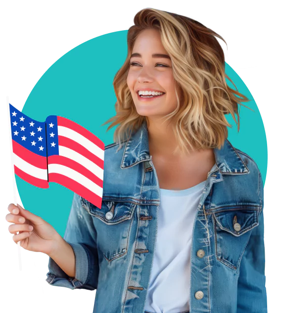 A smiling young woman wearing a light blue denim jacket over a white t shirt, holding a small American flag.