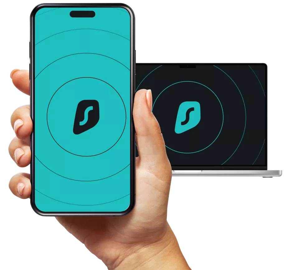Hand holding a smartphone and a laptop displaying the Surfshark logo with concentric circles on a black background.