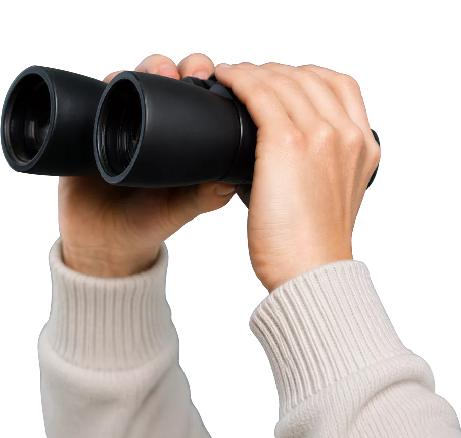 Hands wearing a beige sweater holding black binoculars.